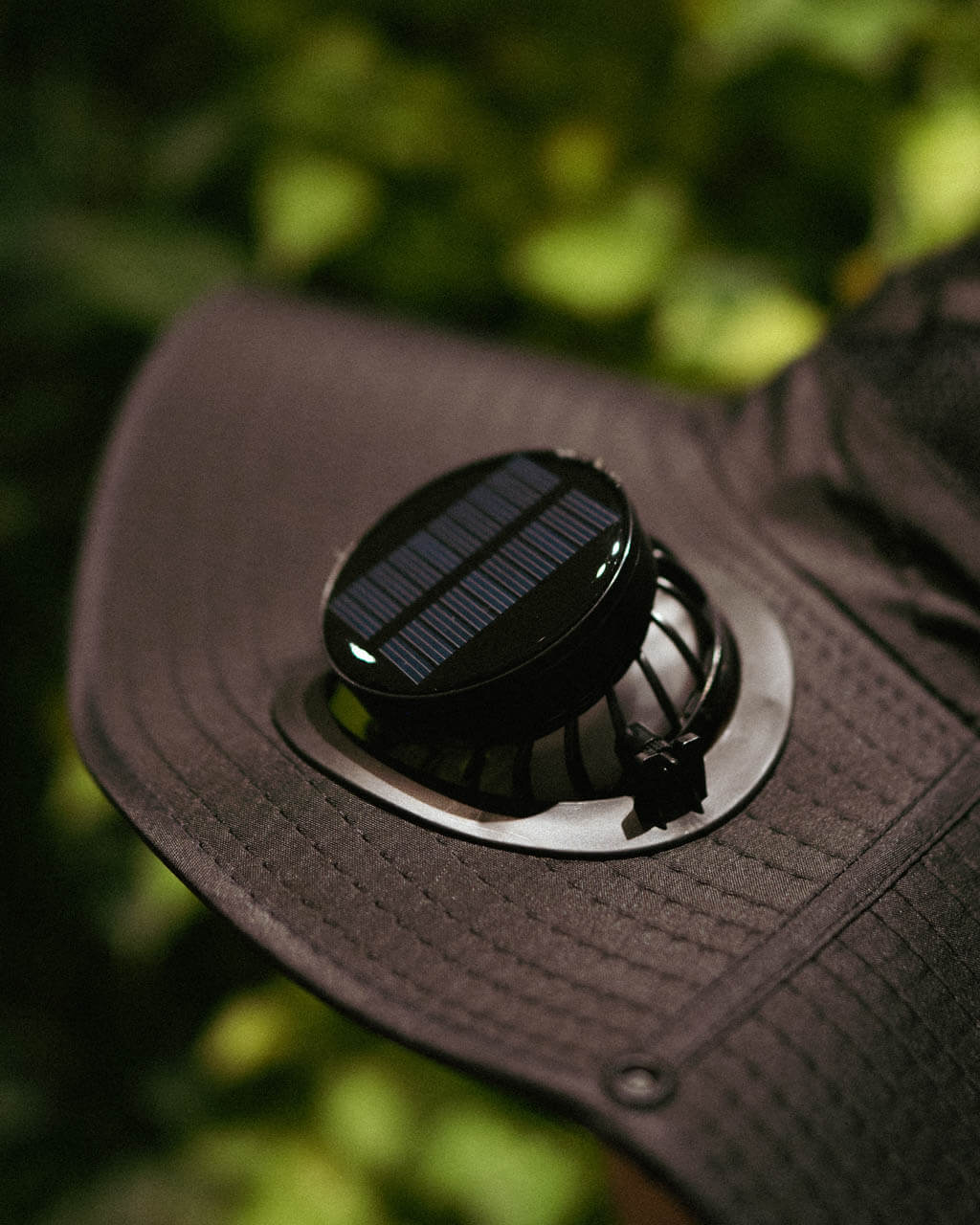 Solar-powered cooling fan attached to FannyCap sun hat outdoors under natural light