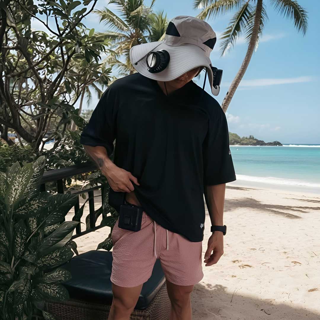 Man wearing FannyCap solar fan cooling hat on tropical beach for sun protection and comfort