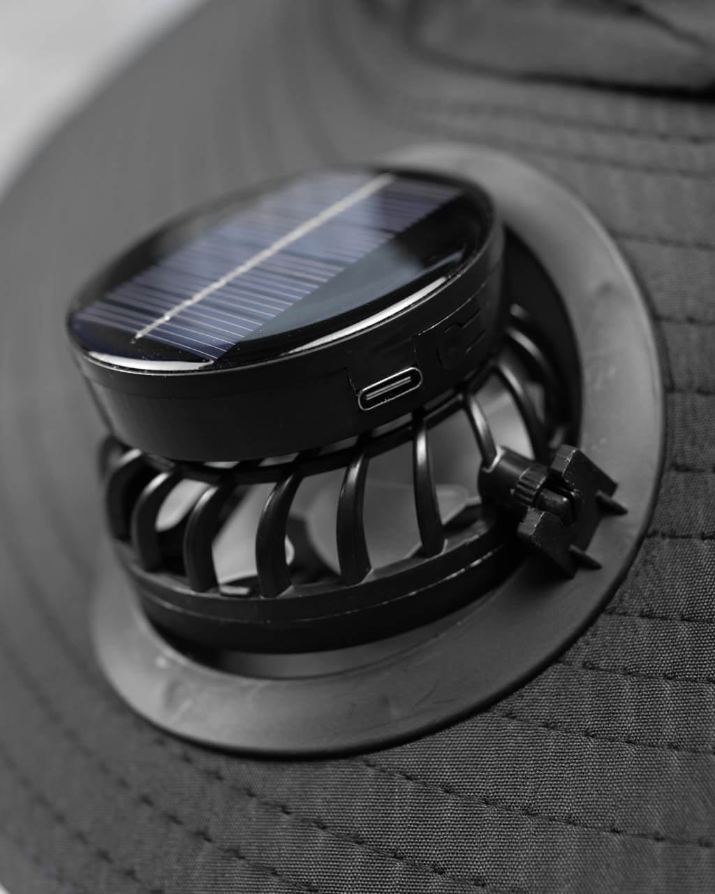 Detachable solar-powered fan for FannyCap hat showing USB-C port and airflow grill